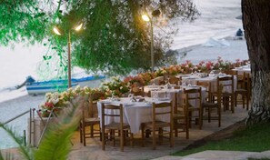 An outdoor dining area with tables set for a meal, overlooking a beach.