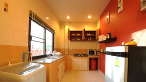 A compact kitchen with a gas stove, microwave, and a refrigerator. - Ruankasalong Hua Hin Holiday House (Hua Hin)