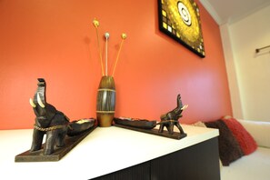 A shelf with elephant figurines, a striped vase, and a decorative piece against a red wall. - Ruankasalong Hua Hin Holiday House (Hua Hin)