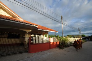 A residential building with a red and white facade, a gated entrance, and a clear sky. - Ruankasalong Hua Hin Holiday House (Hua Hin)