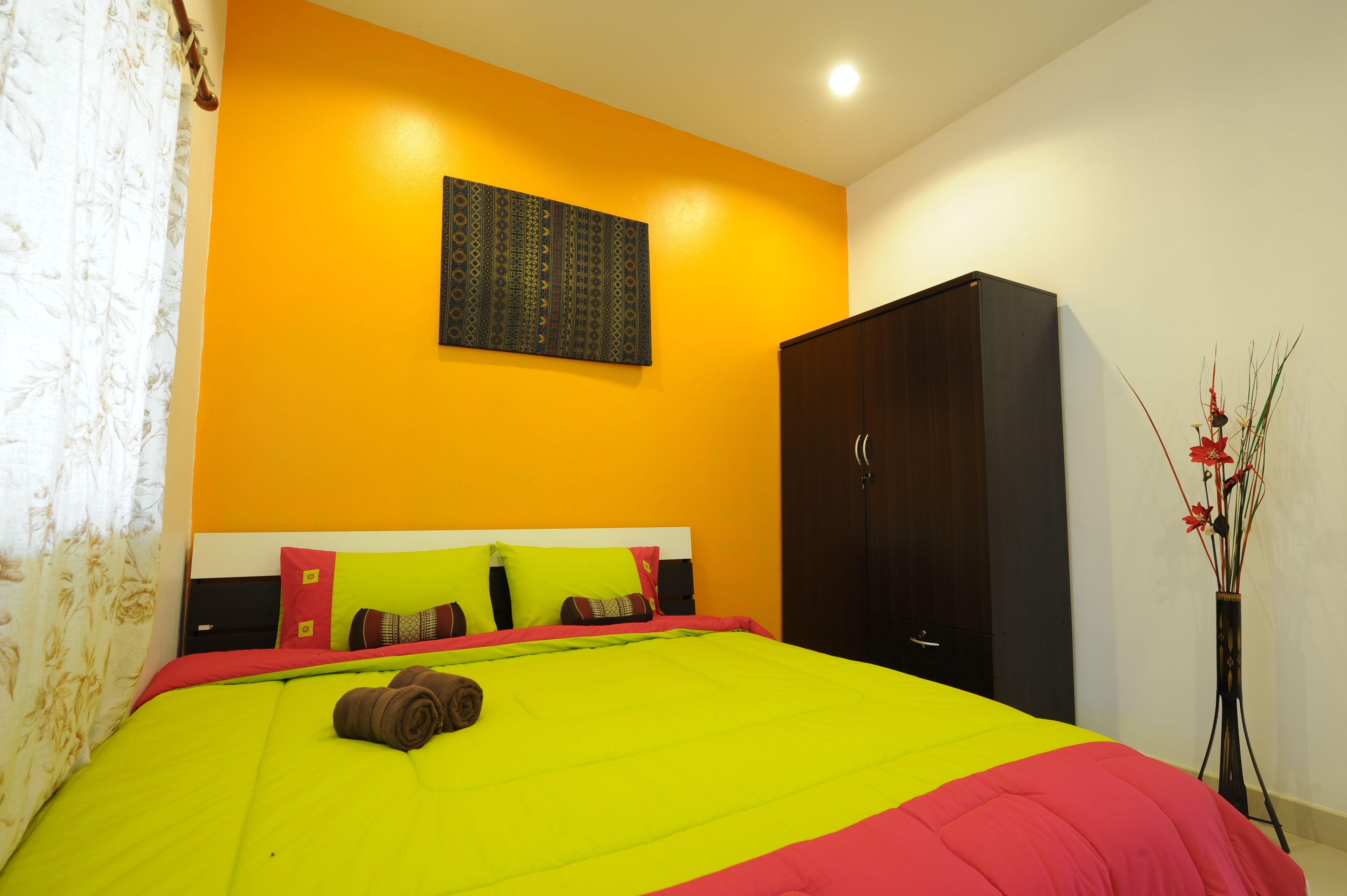 A hotel room with a bed, a wardrobe, and a wall-mounted artwork.