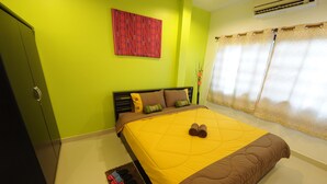 A bedroom with a bed, green walls, a red abstract painting, a window with curtains, and a wardrobe. - Ruankasalong Hua Hin Holiday House (Hua Hin)