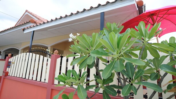 A house with a red roof, white fence, and green plants in front. - Ruankasalong Hua Hin Holiday House (Hua Hin)