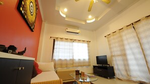 A hotel room with a bed, a glass coffee table, a television, and a ceiling fan. - Ruankasalong Hua Hin Holiday House (Hua Hin)