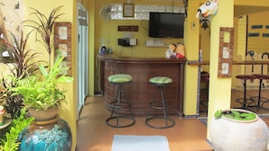 A bar area with stools, a television, and decorative items. - Pius Place (Pattaya)