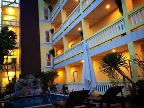 A multi-story hotel with outdoor seating and a pool area.