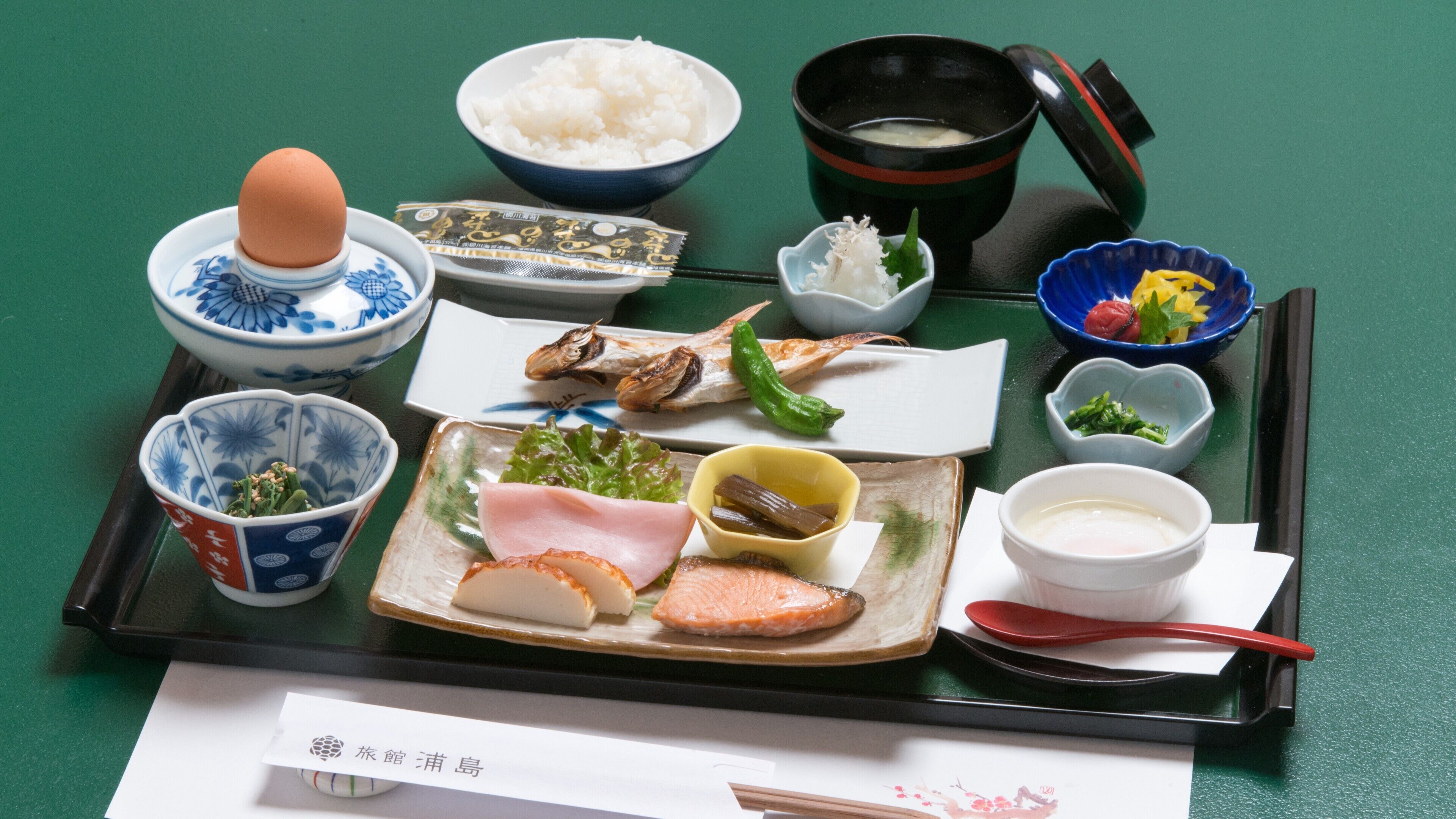 A tray with various Japanese dishes including rice, fish, and vegetables.