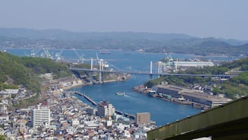 Un paisaje urbano costero con un puente destacado, edificios urbanos densos y un puerto con barcos.