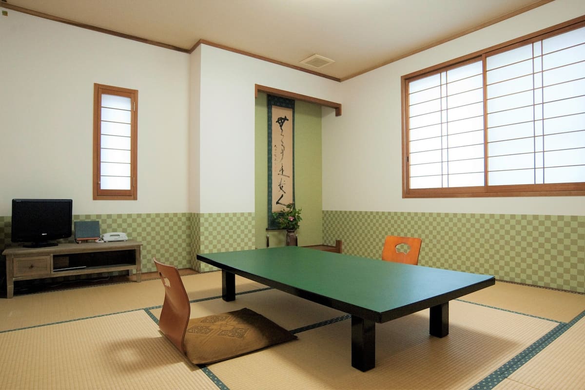 A tatami mat room with a low table, a television, and a traditional Japanese sliding door.
