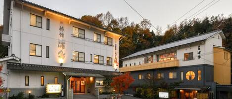 Un edificio de dos pisos con estilo arquitectónico japonés tradicional, que cuenta con una entrada espaciosa y un cartel.