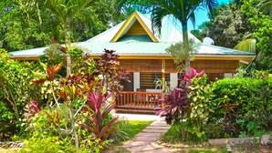 A house with a green roof, surrounded by lush tropical vegetation. - Cocotier Du Rocher (La Digue)