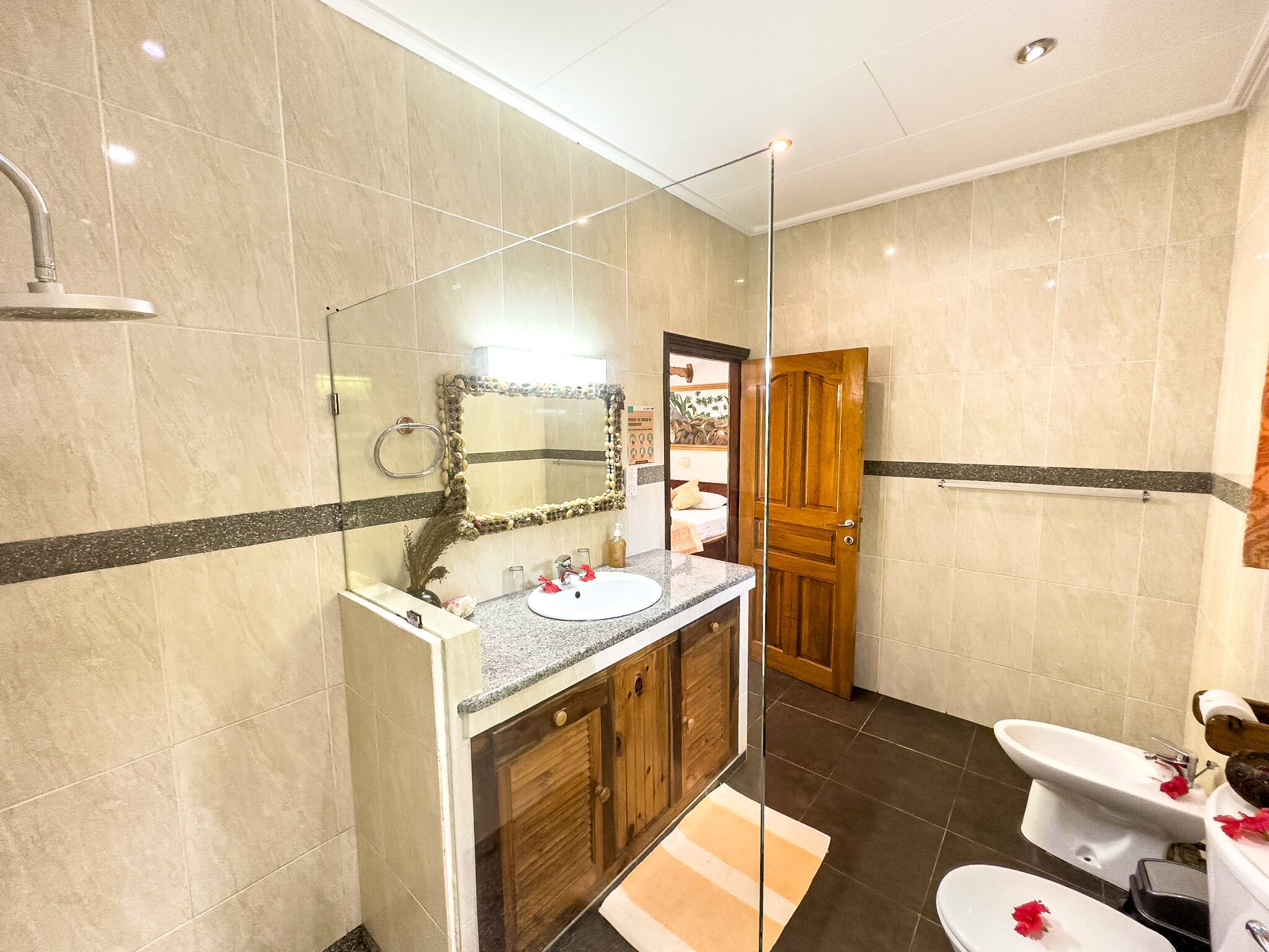 A modern bathroom with a glass-enclosed shower, a wooden vanity with a sink, and a bidet.