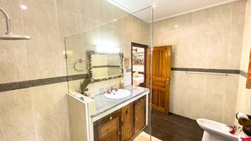 A modern bathroom with a glass-enclosed shower, a wooden vanity with a sink, and a bidet.