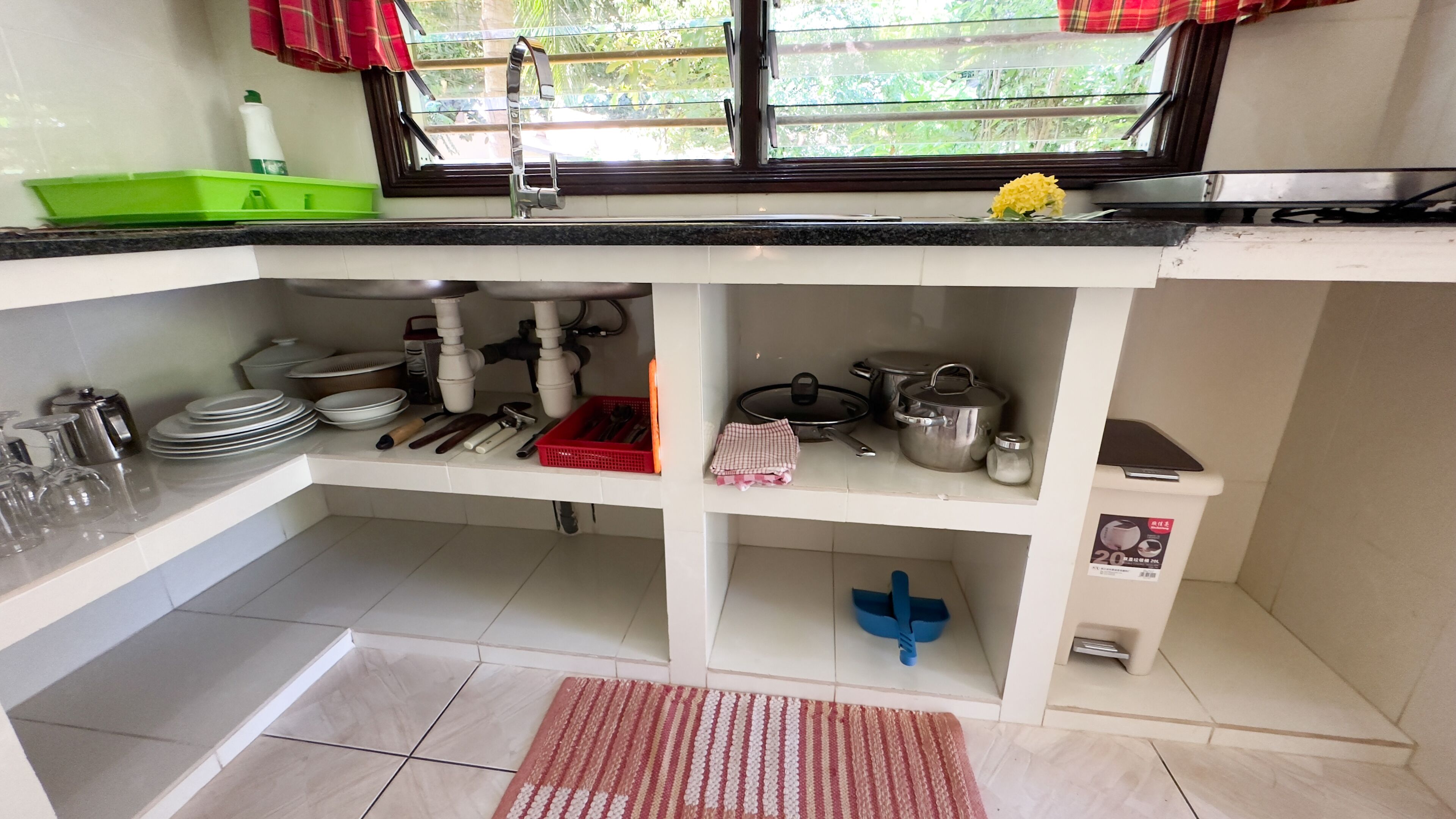 Una cocina con un lavamanos, armarios y una ventana.
