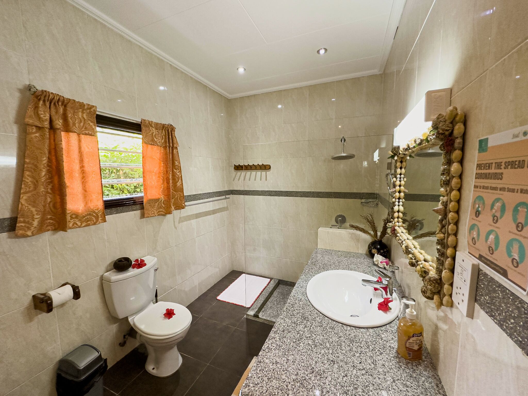 Un baño con inodoro, bidé y lavamanos, ducha y espejo con detalles decorativos.