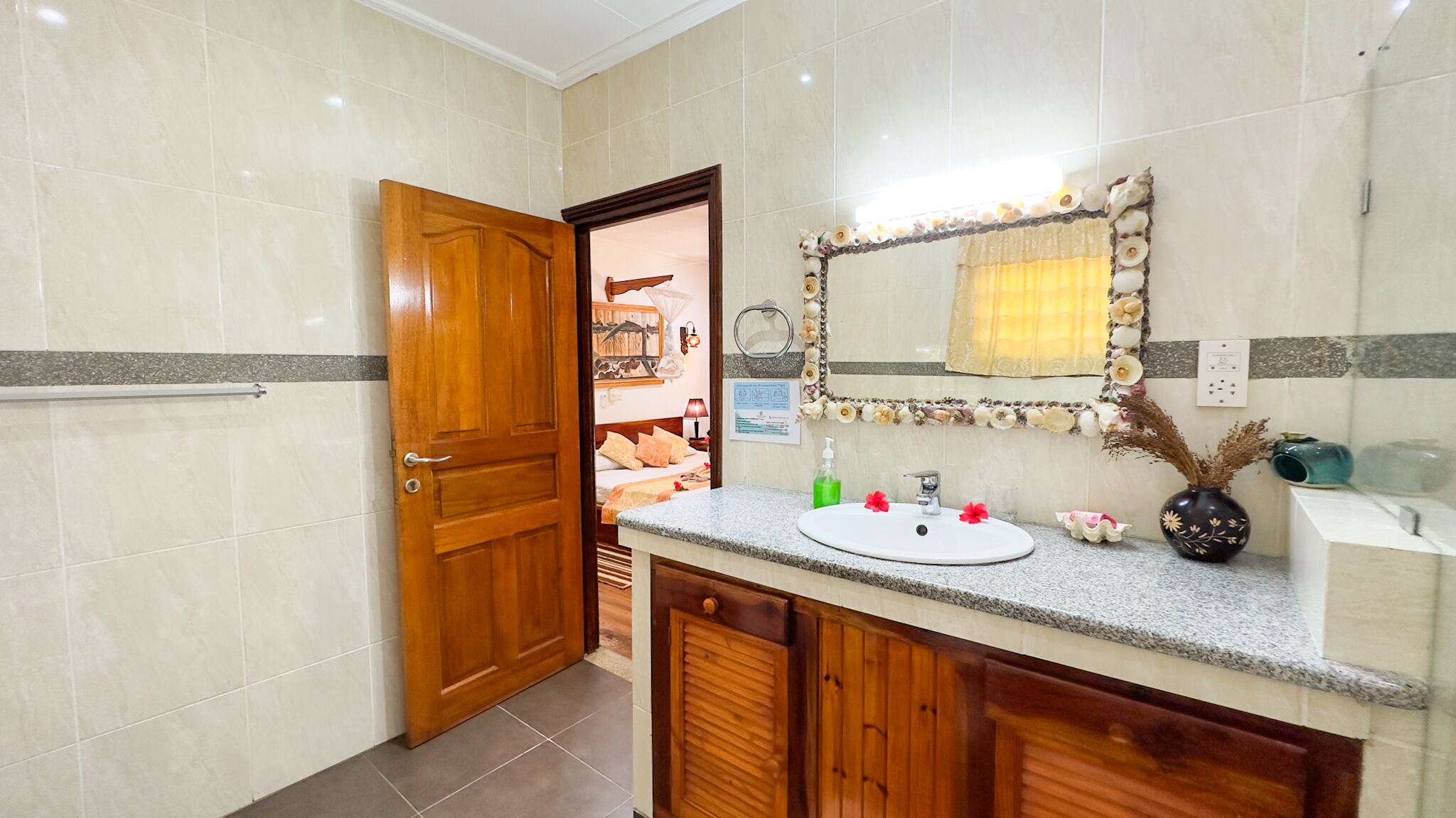 Un baño con puerta de madera, un lavabo con espejo y zona de ducha.