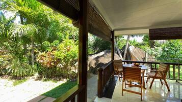A balcony with a view of a lush garden and a large rock formation.