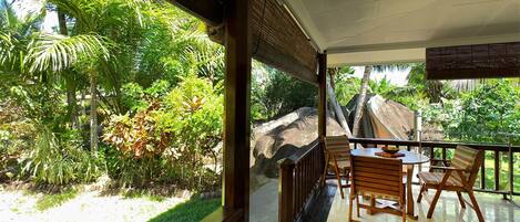 A balcony with a view of a lush garden and a large rock formation.