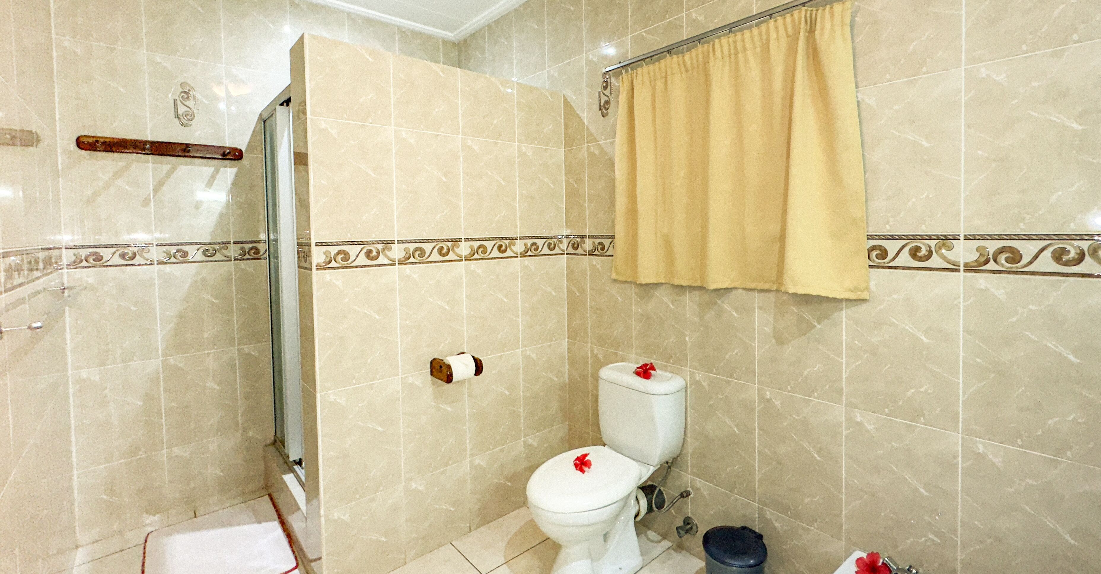 A bathroom with a toilet, shower, and a towel rack.