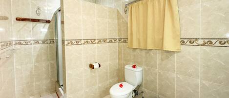 A bathroom with a toilet, shower, and a towel rack.