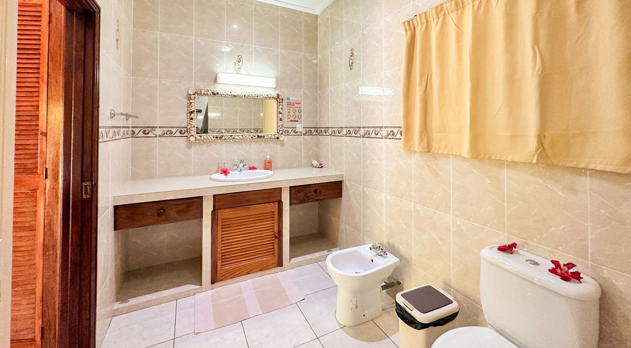 A bathroom with a sink, bidet, toilet, and a mirror with decorative tiles.