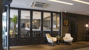 Een modern interieur met grote glazen deuren, een keukenhoek, twee witte stoelen en een statief.