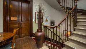A wooden door, a vase with branches, a staircase with a handrail, and a framed picture on the wall. - Villa St Simon (Blaye)