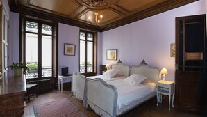 A bedroom with a double bed, bedside tables, a nightstand, a potted plant, and a view through a window. - Villa St Simon (Blaye)
