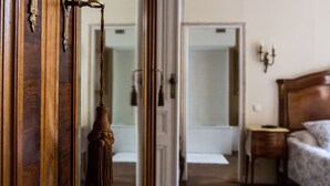 A room with a wooden door, a bed with a patterned bedspread, a bedside table, and a wall-mounted lamp. - Villa St Simon (Blaye)
