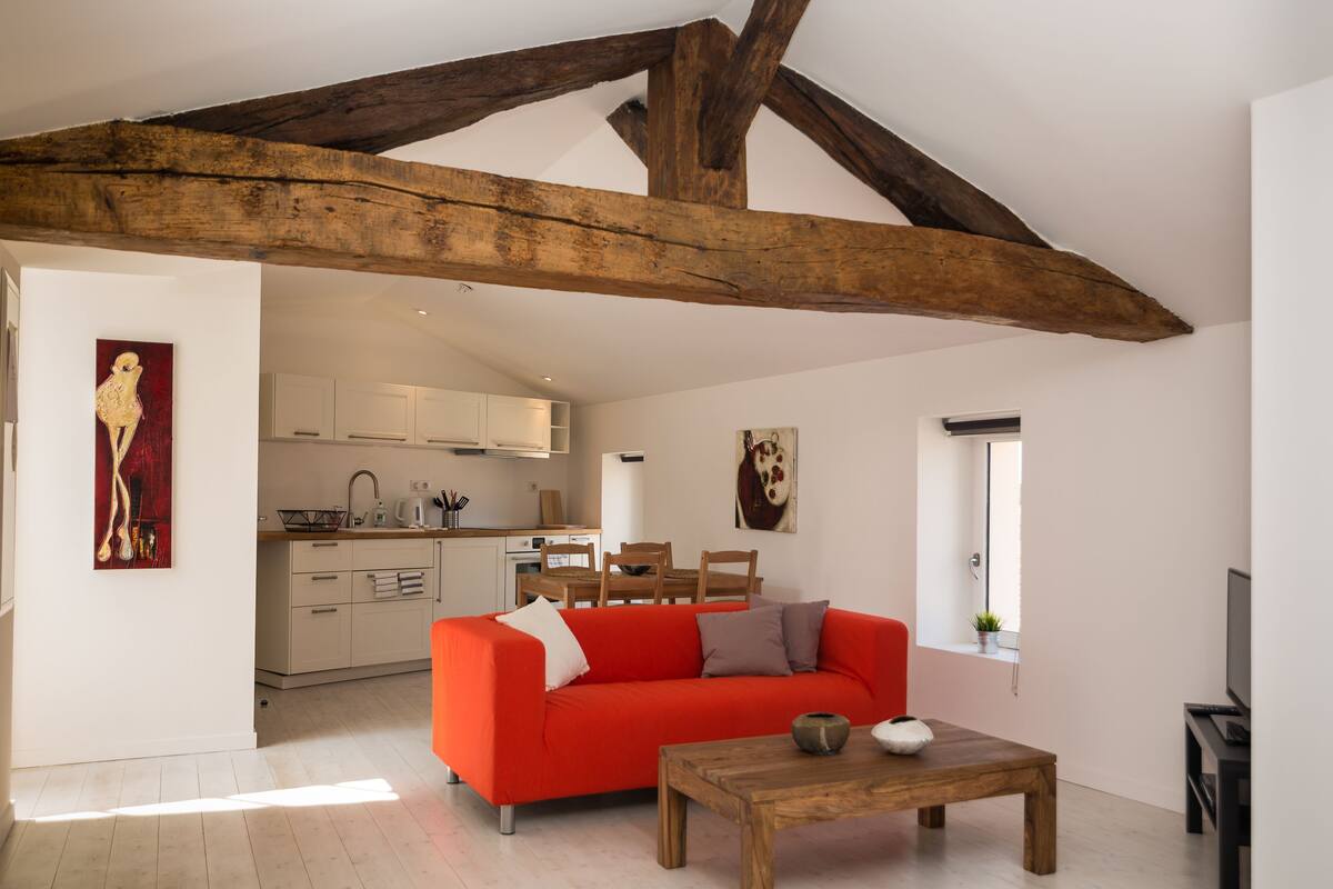 A living room with a red sofa, wooden coffee table, and exposed wooden beams.