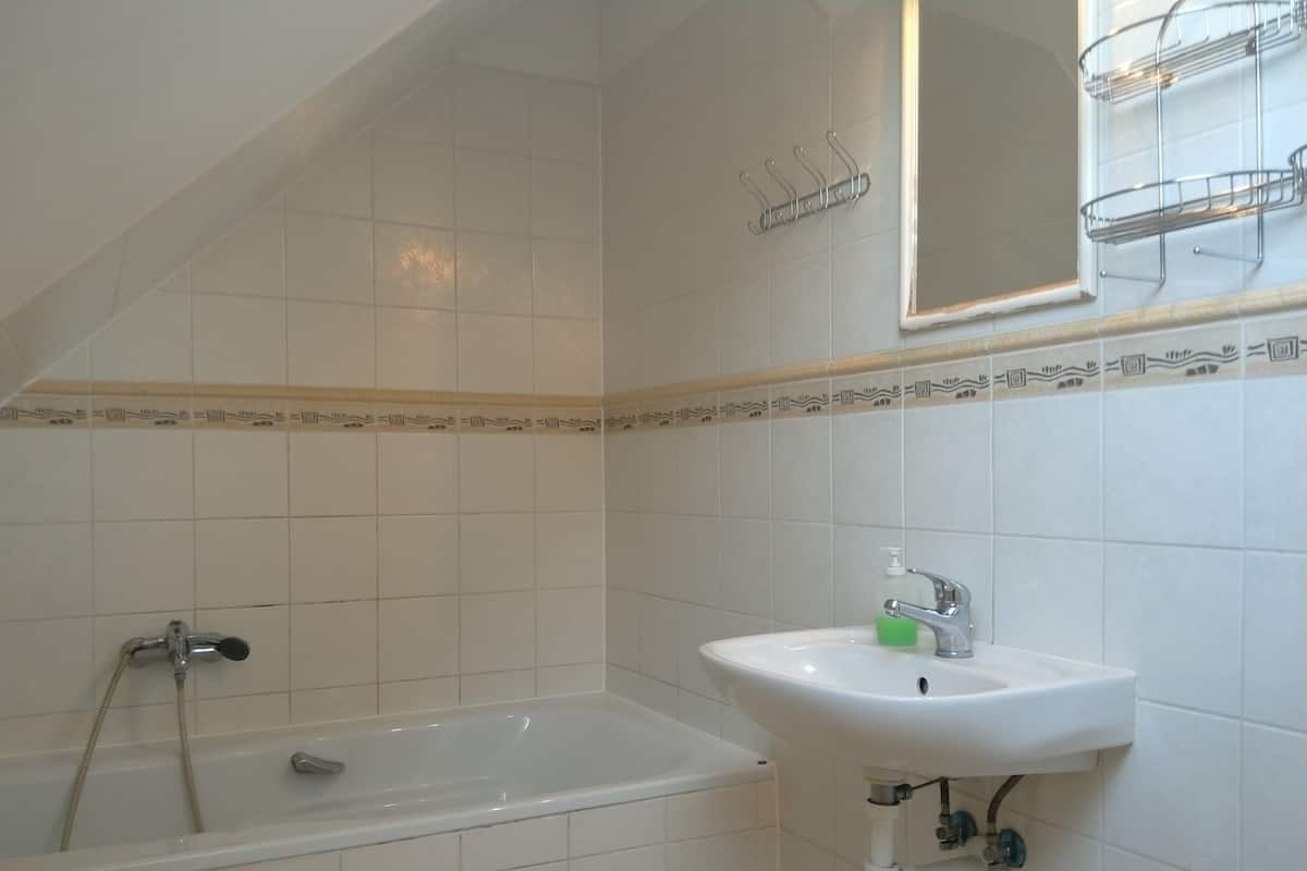 Un baño con bañera, lavamanos y espejo.