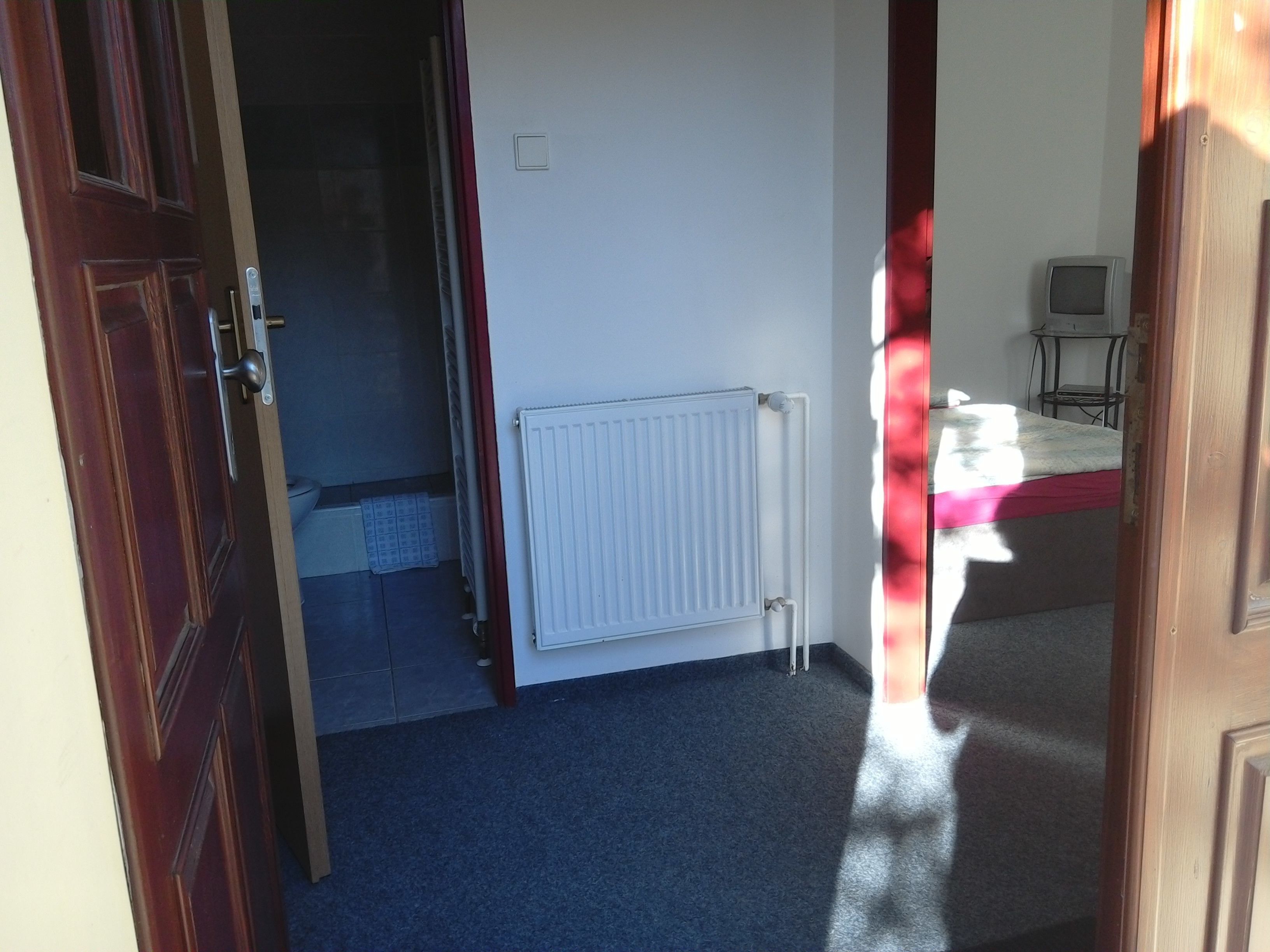 A room with a radiator, a bed, and a small table with a chair.