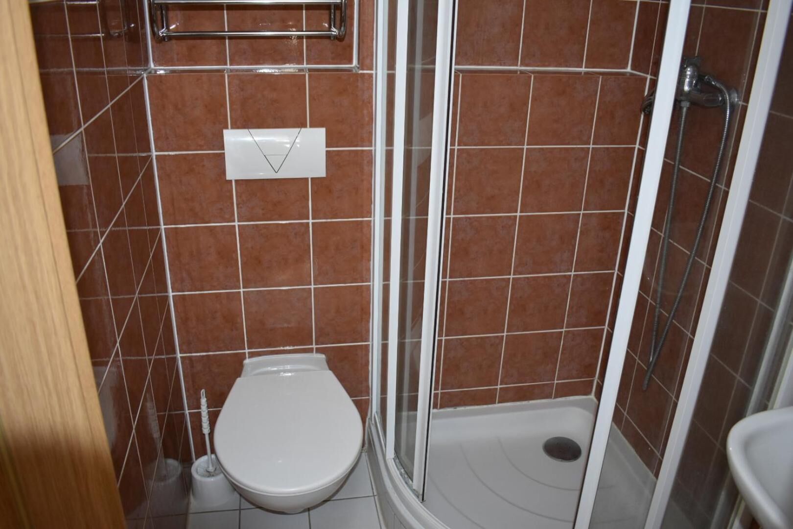 A bathroom with a toilet, shower, and a towel rack.