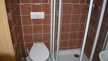 A bathroom with a toilet, shower, and a towel rack.