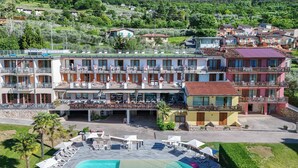 Un hotel con piscina, mobiliario exterior y varios balcones.