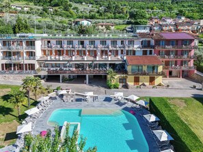 A hotel with a swimming pool, outdoor seating, and multiple balconies. - Park Hotel Val di Monte (Malcesine)