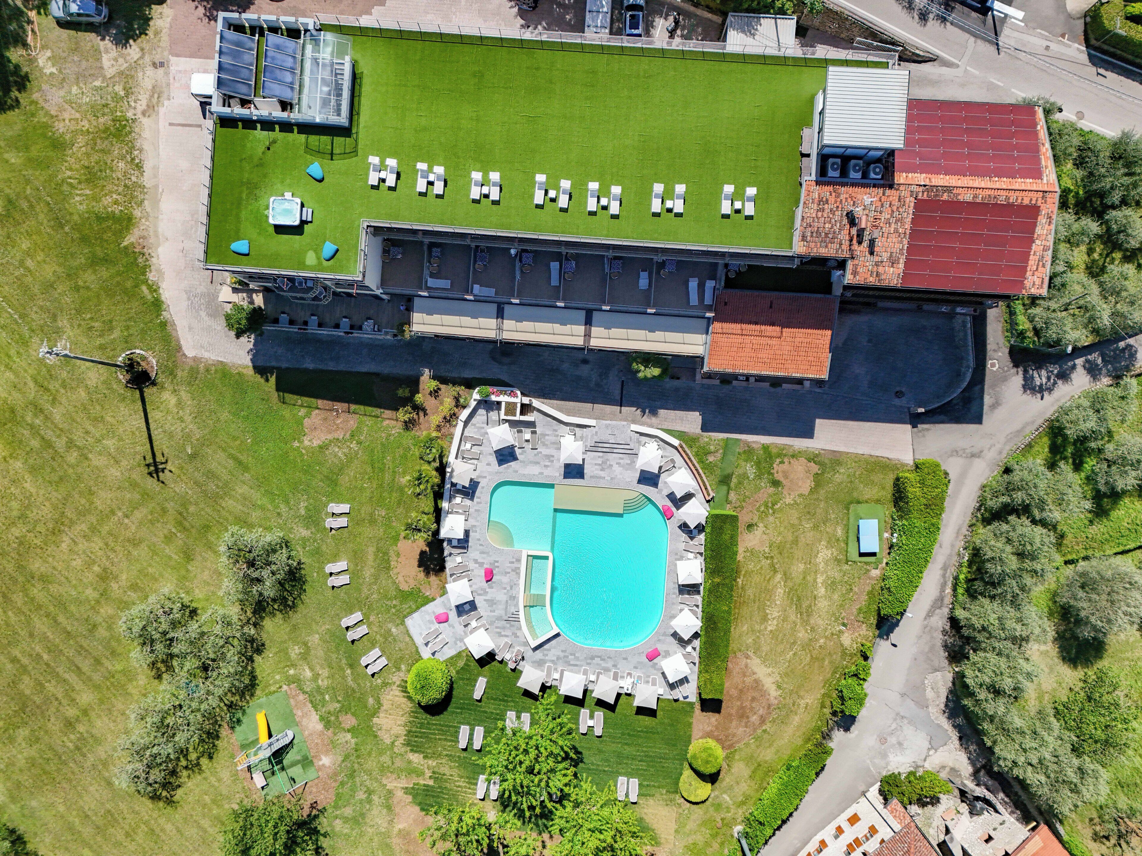 Eine Luftaufnahme eines Hotels mit Schwimmbad, Liegestühlen und einem überdachten Außenbereich.