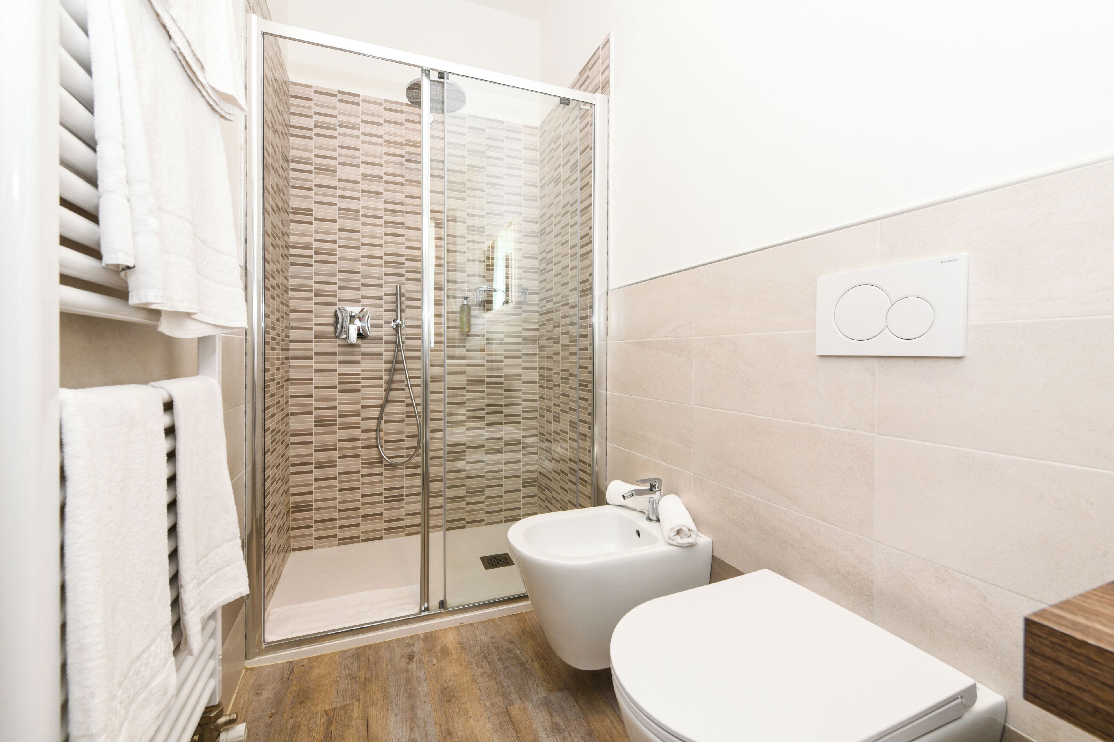 A modern bathroom with a glass-enclosed shower, a bidet, and a toilet.