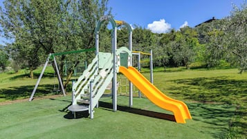 Une aire de jeux avec un toboggan et des balançoires.