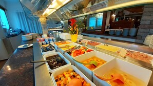 Un bufé con diversas opciones de comida, incluyendo frutas, verduras y carnes.