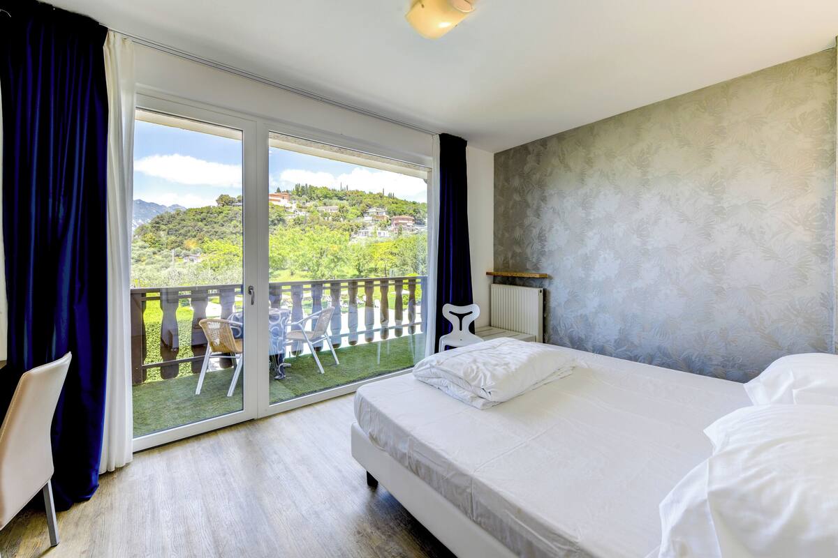 Ein Schlafzimmer mit einem großen Bett, Balkonblick und einer Wand mit Muster.