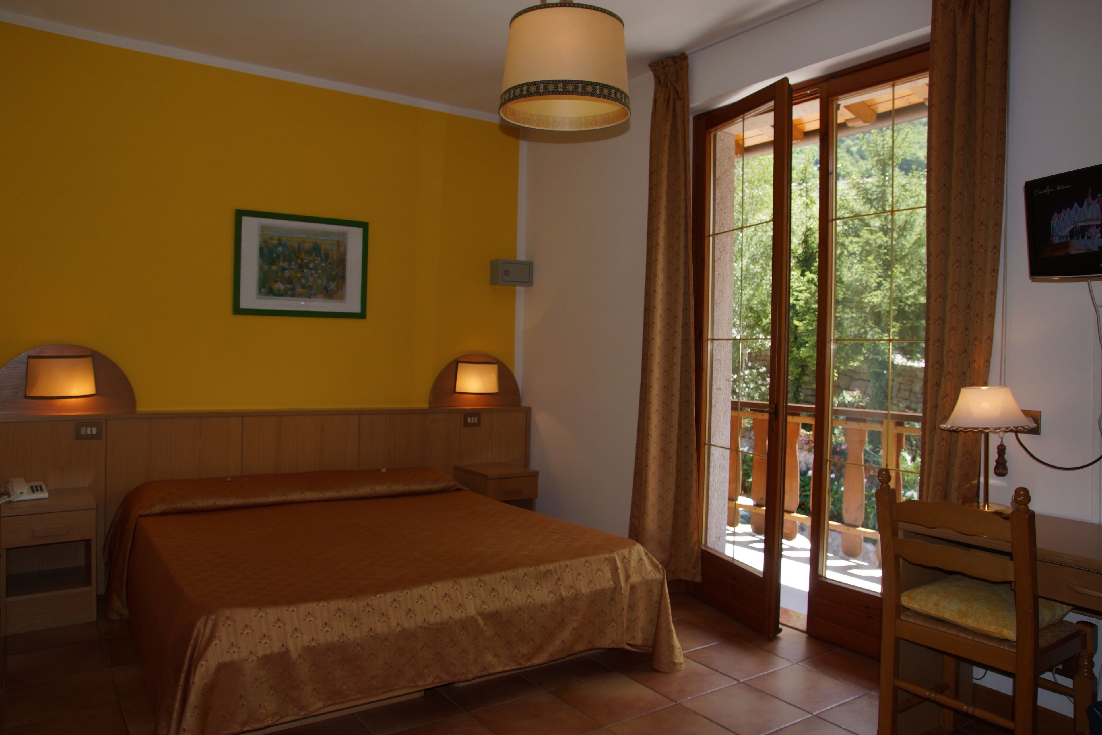 A bedroom with a bed, two bedside lamps, a nightstand, a chair, and a window with curtains.