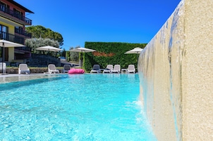Una piscina al aire libre de temporada, sombrillas
