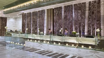 A reception area with marble walls, a glass barrier, and reception desks.