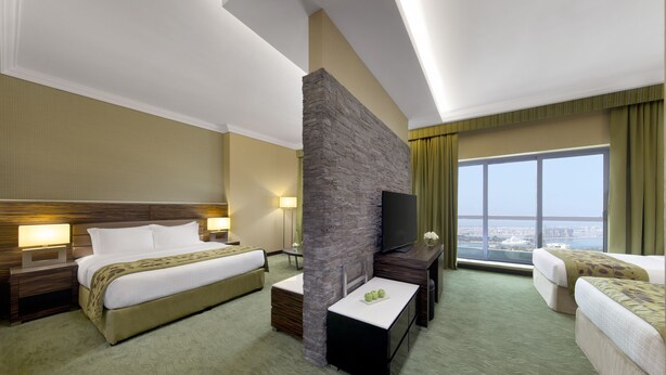 Ein Hotelzimmer mit zwei Betten, einem Fernseher, einer Wand mit Steinakzenten und Blick auf die Stadt.