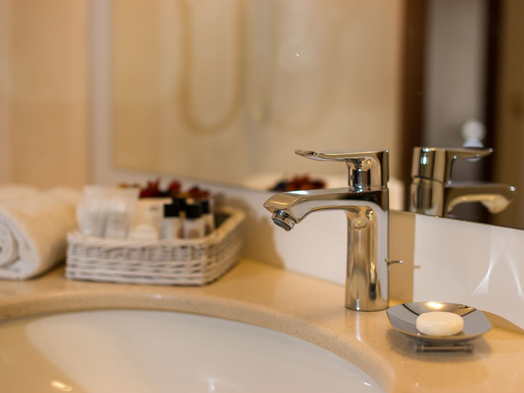 A bathroom sink with a chrome faucet, a soap dish, and a basket of toiletries.