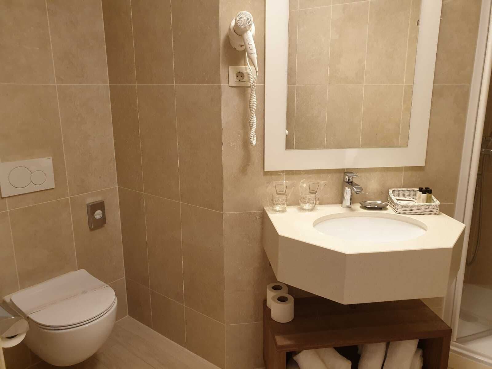 A bathroom with a toilet, sink, and shower.