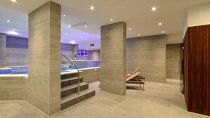 A modern spa area with a hot tub, tiled walls, and a wooden bench. - Aparthotel Miramare (Makarska)