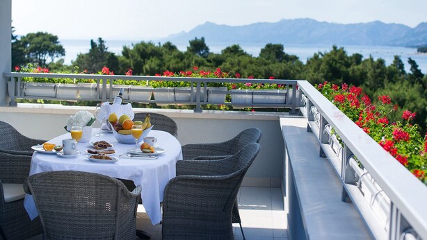 A dining table set with breakfast items and a view of the sea and mountains. - Aparthotel Miramare (Makarska)