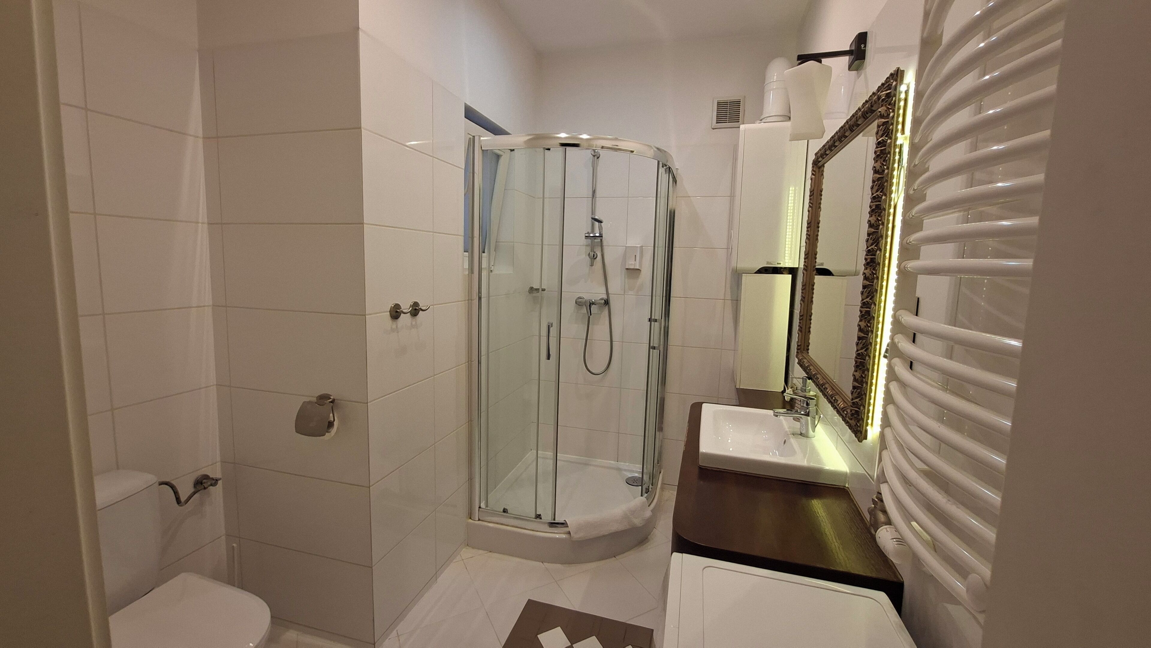 A modern bathroom with a glass-enclosed shower, a white sink, and a vanity with a mirror.